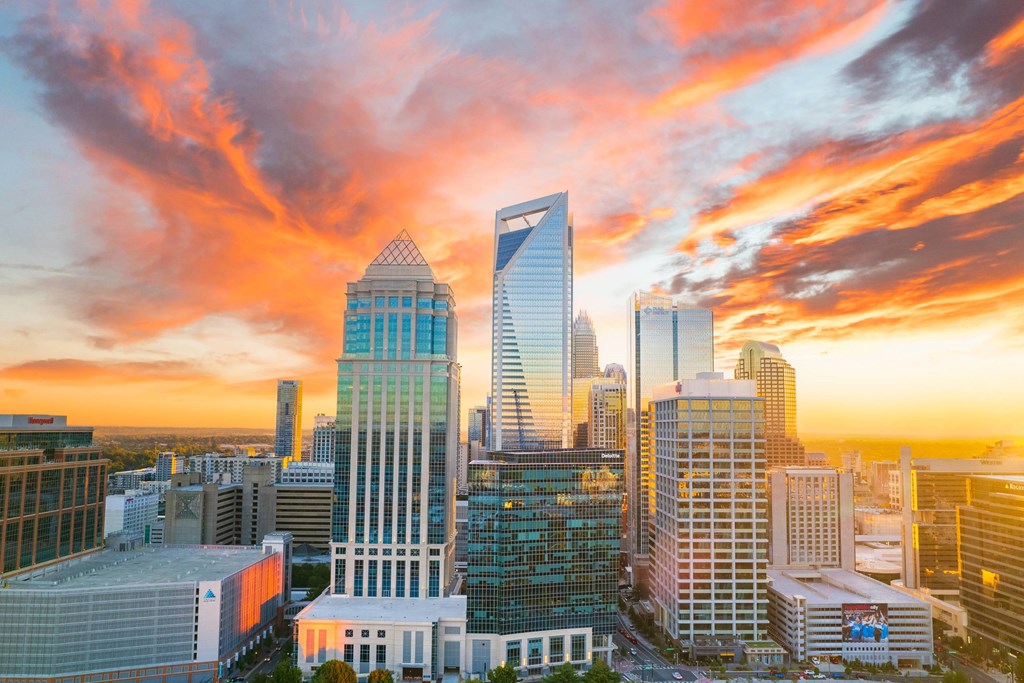 A city skyline at sunset with buildings of various shapes and sizes.