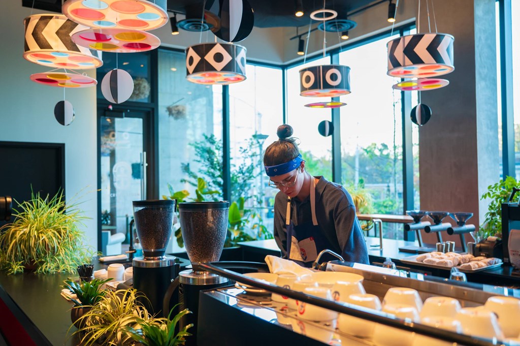 A person is making a smoothie at a counter with a blender.
