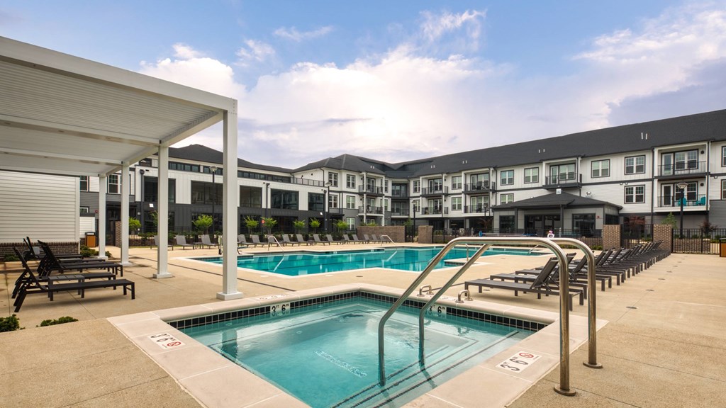 A swimming pool in a sunny day with a building in the background.