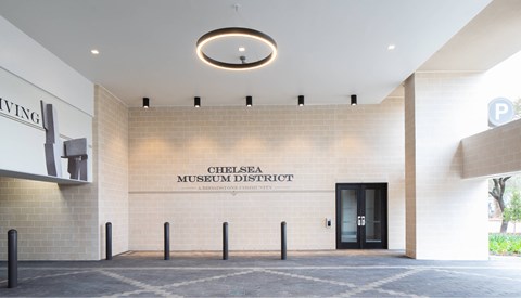 The Chelsea Museum District building has a modern design with a black door and a white wall.
