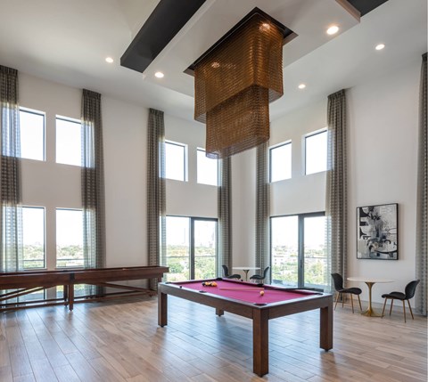 A pool table in a room with a view of the outdoors.