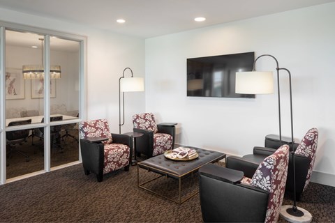 A modern living room with a glass door, a sofa, a chair, a coffee table, and a lamp.