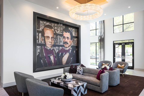 A living room with a large painting of two men, a grey sofa, and a coffee table.