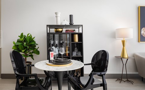 A black chair sits in front of a white table with a plant on it.