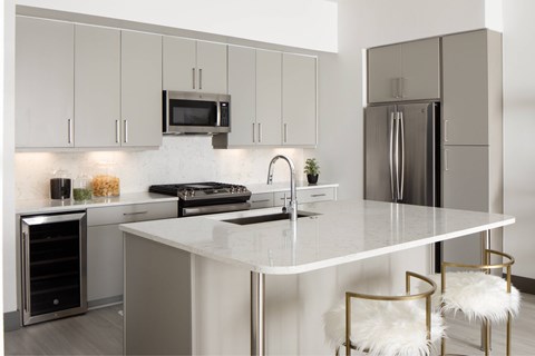 A modern kitchen with a white island and stainless steel appliances.
