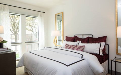 A bedroom with a large bed and a window with a view of trees.