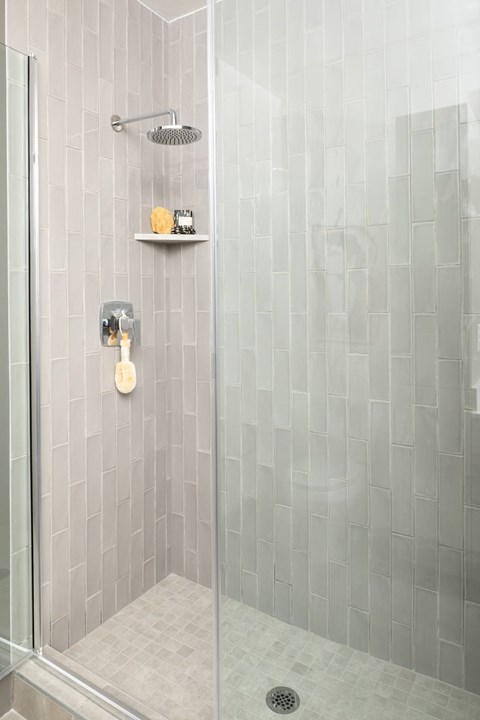 A shower with a glass door and a tiled wall.