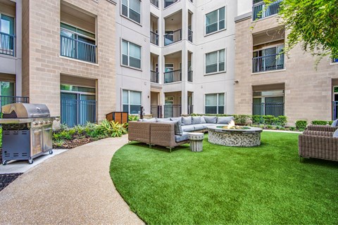 A patio with a fire pit and seating area in front of a building.