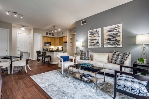A modern living room with a white sofa, a coffee table, and a dining table.