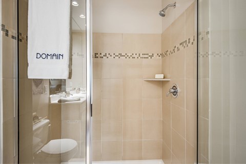 A bathroom with a towel that says "DOMAIN" hanging on the door.