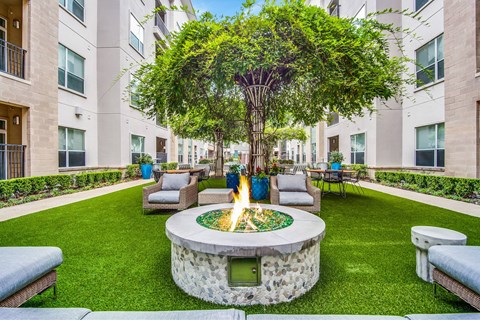 A tree in a courtyard with a fire pit in the middle.