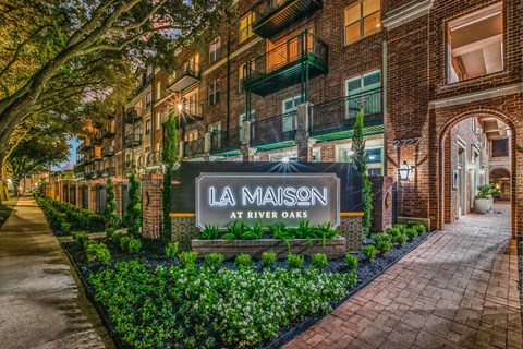 A sign that says La Maison at River Oaks in front of a building.