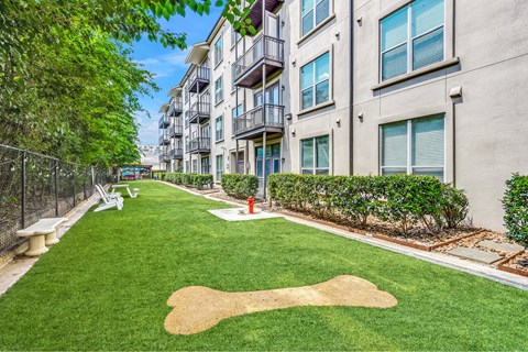 A grassy area with a baseball diamond painted on it in front of apartment buildings.