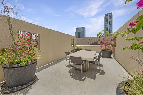 A patio with a table and chairs surrounded by potted plants.