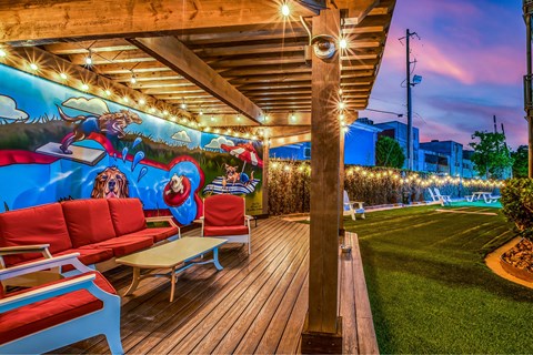 A wooden deck with red couches and a mural of a landscape with animals.