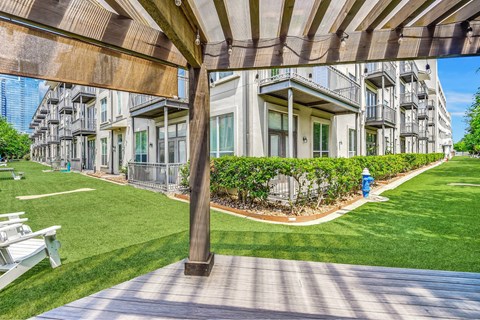 A wooden pergola is over a grassy area.