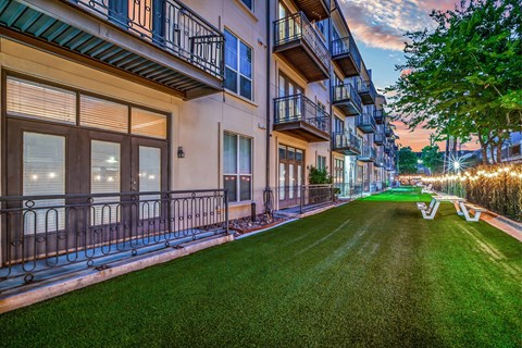 A well-lit apartment complex with a green lawn in front.