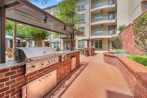 A patio with a grill and a brick wall.