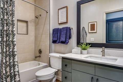 A bathroom with a white toilet, a white sink, a white bathtub, and a blue towel.