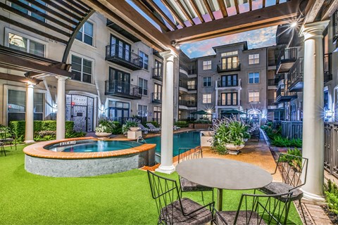 A patio with a table and chairs overlooking a pool.
