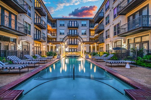 A pool in the middle of a courtyard surrounded by buildings.