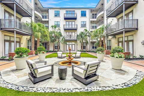 A courtyard with a fountain and seating area in front of apartment buildings.