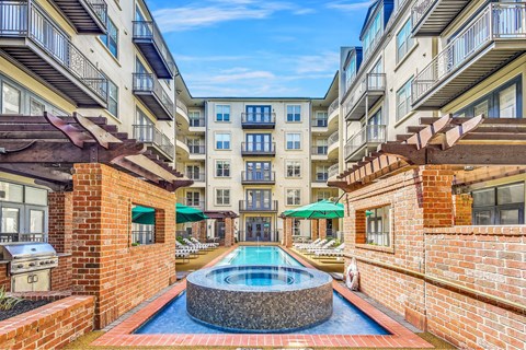 A pool in the middle of a courtyard surrounded by brick walls.