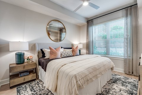 A bedroom with a large bed and a round mirror on the wall.