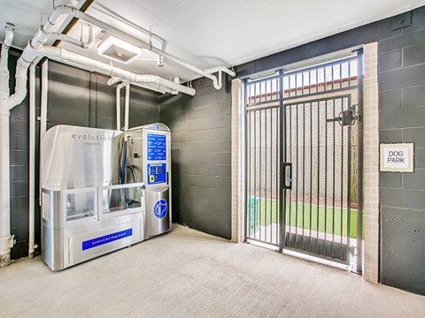 A dog park with a water fountain and a gate.