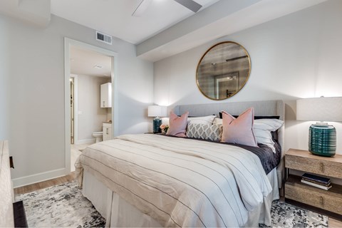 A bedroom with a large bed and a round mirror above it.
