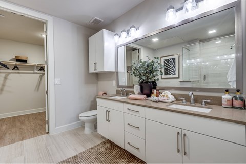 A bathroom with a white toilet and a large mirror above the sink.