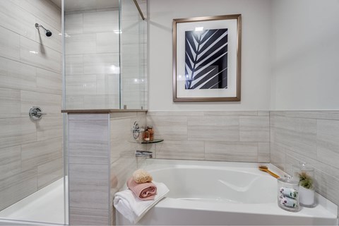 A white bathtub with a towel and a picture frame on the wall.