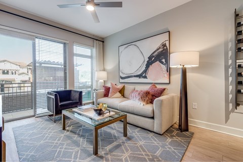 A living room with a blue rug and a painting on the wall.