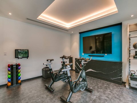 A room with a television, a bicycle, and a colorful object on the floor.