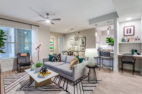 A living room with a grey couch, a coffee table, and a ceiling fan.