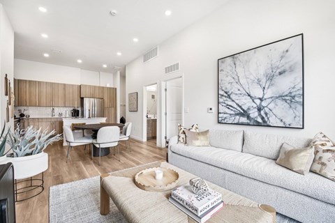A modern living room with a grey sofa, a coffee table, and a large painting on the wall.