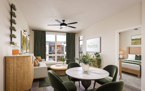 A living room with a round table and green chairs.