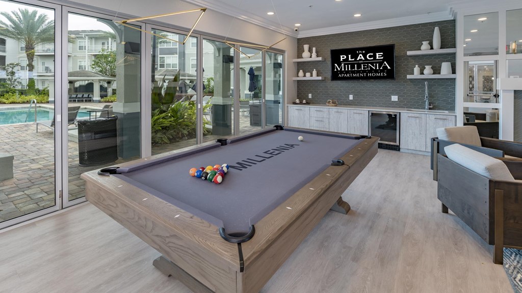 A pool table in a room with a sign that says "Place Millenia".