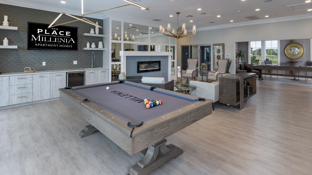 A pool table is in the middle of a room with a sign that says Place Millenia Apartment Homes.