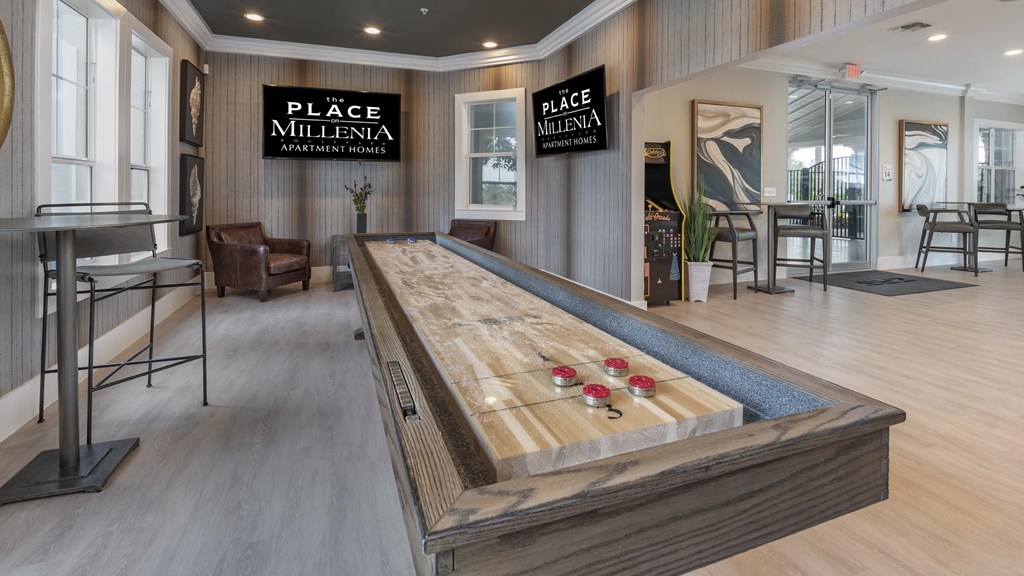 A shuffleboard table is in the middle of a room with wood floors and wood panel walls.