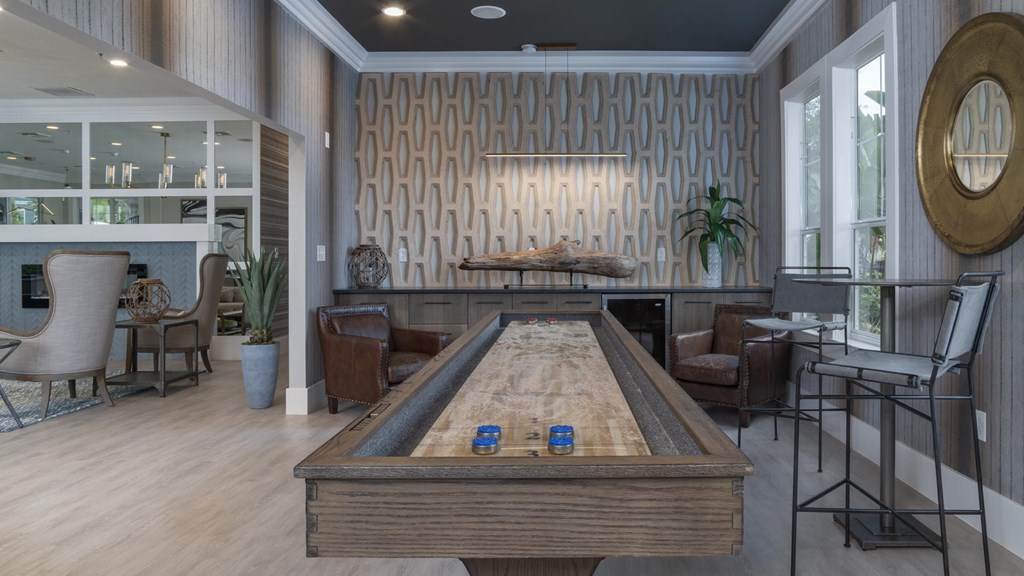 A pool table is surrounded by chairs in a room with a wood grain wallpaper.