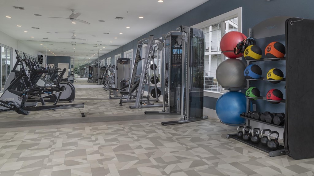 A gym with a variety of equipment including weights and exercise balls.