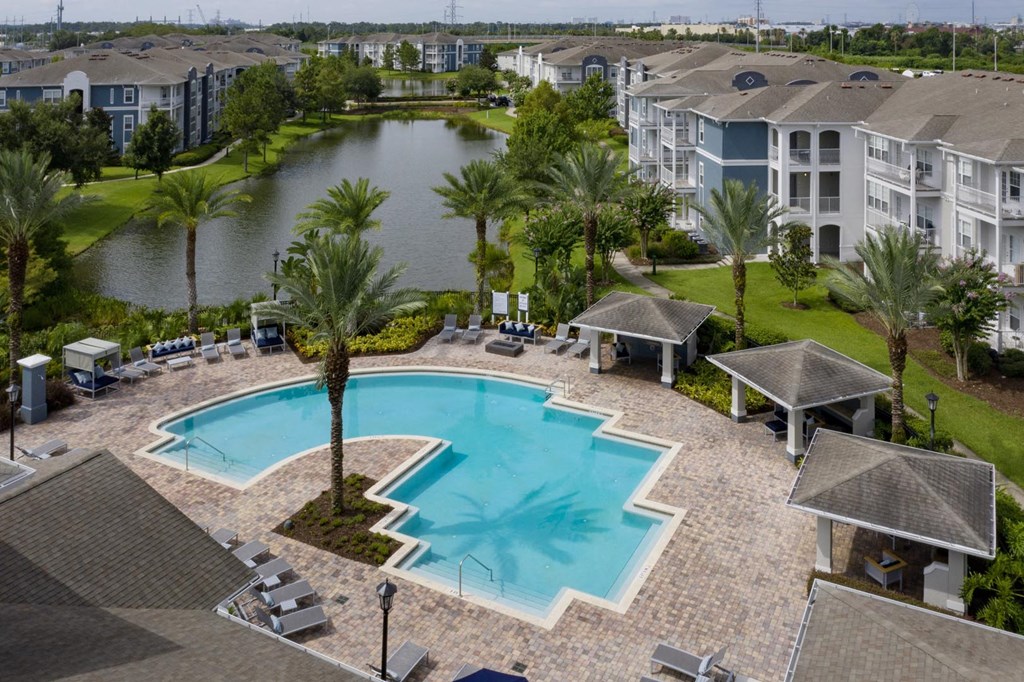 A swimming pool surrounded by palm trees and apartment buildings.