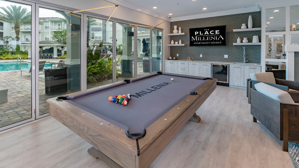 A pool table in a room with a sign that says "Place Millenia".