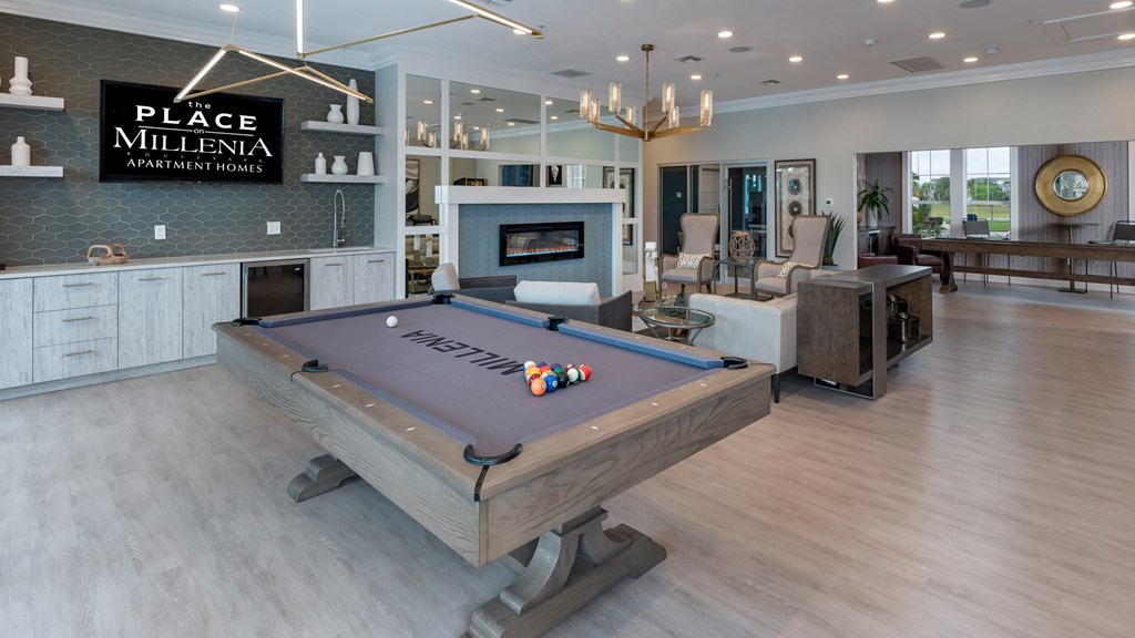 A pool table in a room with a sign that says Place Millenia Apartment Homes.