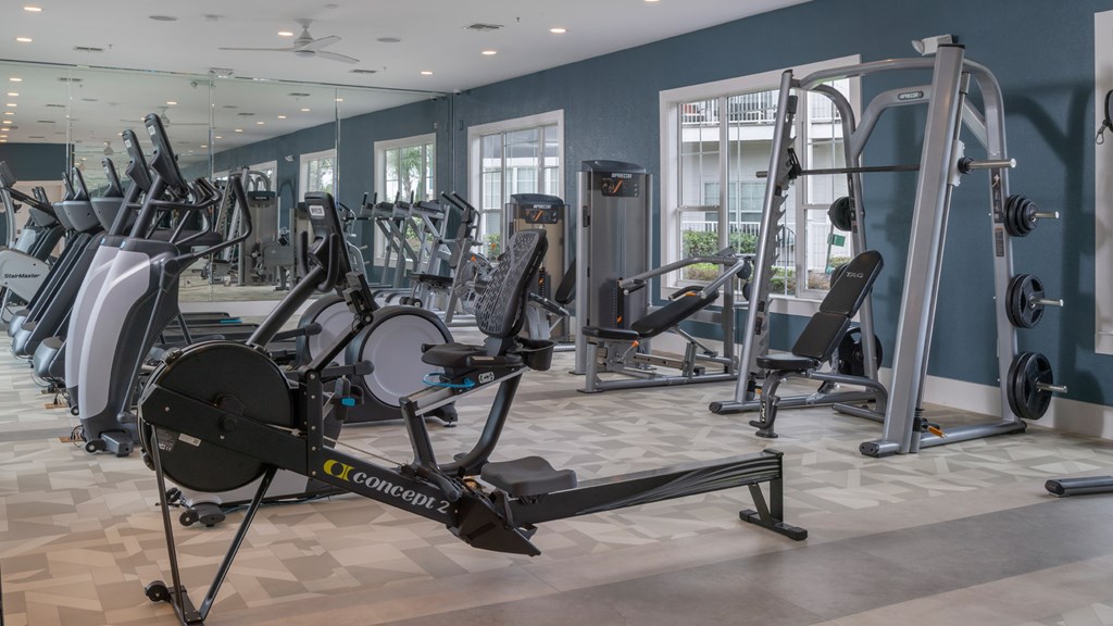 A gym with a variety of exercise equipment including treadmills, stationary bikes, and weight machines.