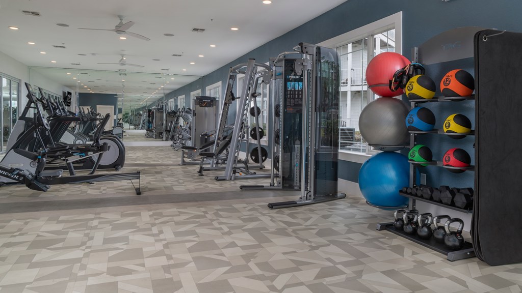 A gym with a variety of equipment including weights and exercise balls.