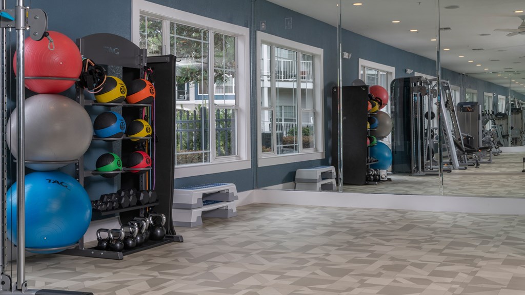 A gym with a variety of equipment including weights and exercise balls.