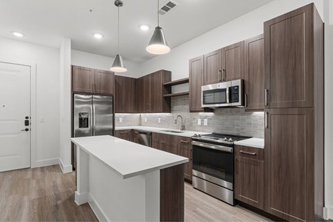 A modern kitchen with dark wood cabinets and stainless steel appliances.