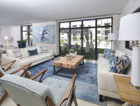 A modern living room with a white couch, a wooden coffee table, and a large window.